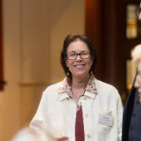 Nancy McCormick smiling at camera while other event guests stand around her